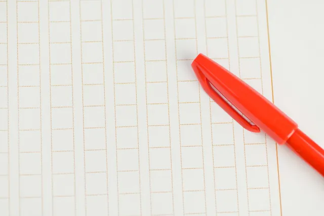 赤ペンで原稿用紙に添削しているイメージ